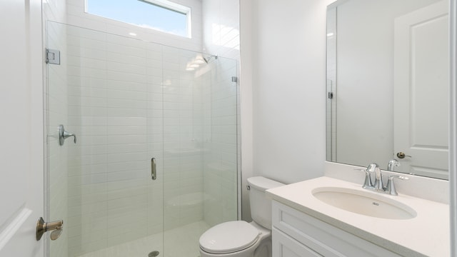 bathroom with vanity, a shower with door, and toilet