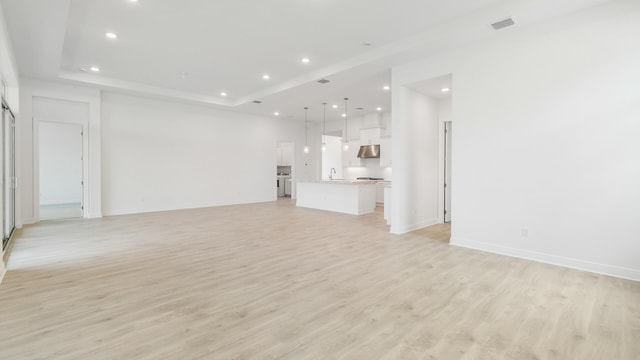 unfurnished living room featuring light wood-type flooring and sink