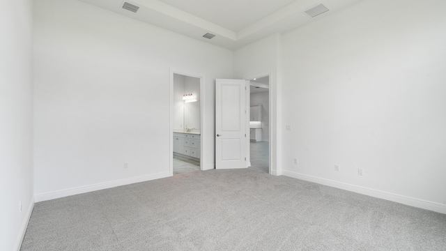 unfurnished bedroom featuring light colored carpet and connected bathroom