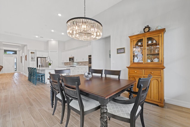 dining space with a high ceiling, light wood-type flooring, and a notable chandelier