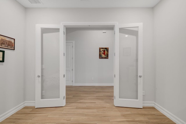 hallway with french doors and light hardwood / wood-style floors