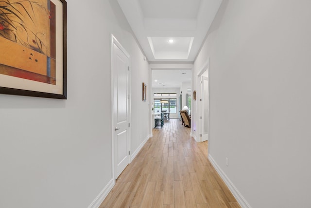 corridor featuring light hardwood / wood-style floors and a raised ceiling