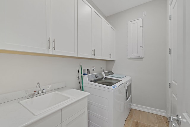 laundry room with electric panel, cabinets, separate washer and dryer, and sink