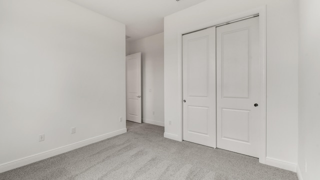 unfurnished bedroom featuring light carpet and a closet