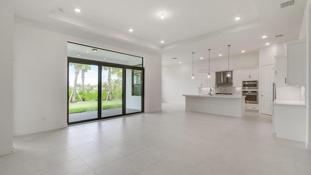 5237 Saint Vincent Ln, Westlake, FL 33470 - unfurnished living room with a raised ceiling, recessed lighting, baseboards, and a sink