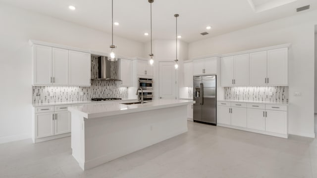 kitchen featuring stainless steel appliances, wall chimney range hood, decorative light fixtures, and white cabinetry