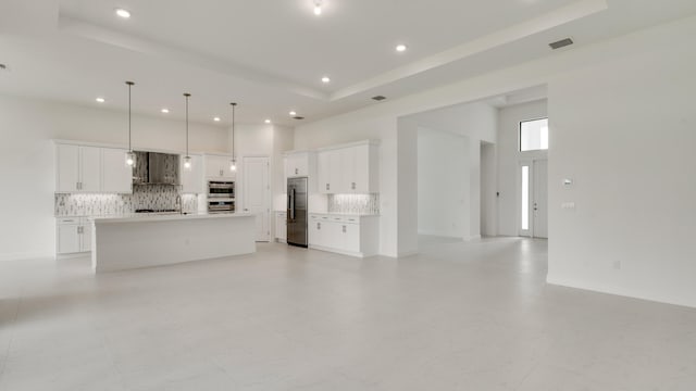 unfurnished living room featuring sink and a raised ceiling