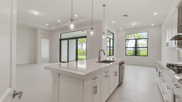 kitchen with sink, hanging light fixtures, appliances with stainless steel finishes, an island with sink, and white cabinetry