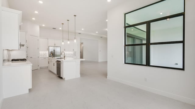 kitchen with a kitchen island with sink, backsplash, hanging light fixtures, white cabinets, and appliances with stainless steel finishes