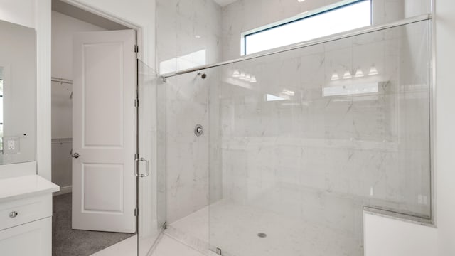 bathroom featuring a shower with shower door and vanity