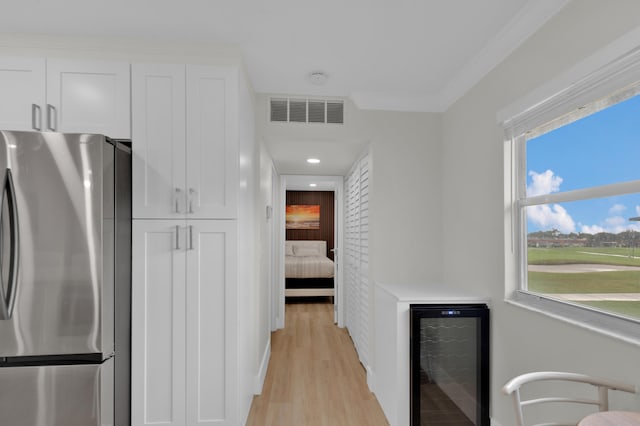 kitchen featuring stainless steel refrigerator, beverage cooler, light hardwood / wood-style flooring, ornamental molding, and white cabinetry