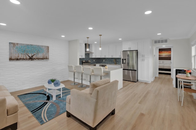 living room with crown molding and light wood-type flooring