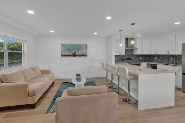 living room with sink, light hardwood / wood-style flooring, and ornamental molding