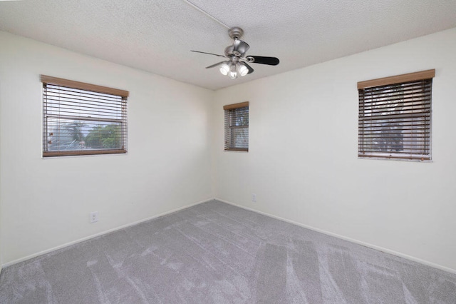 carpeted empty room with ceiling fan, plenty of natural light, and a textured ceiling