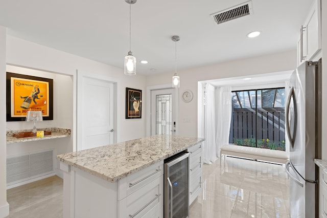 kitchen with stainless steel refrigerator, white cabinetry, beverage cooler, hanging light fixtures, and light stone countertops