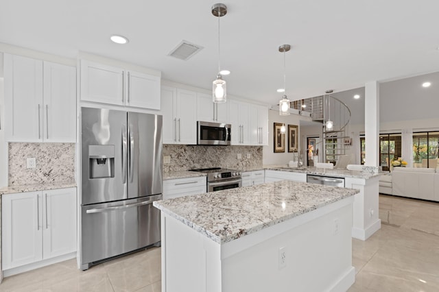 kitchen with stainless steel appliances, white cabinets, a kitchen island, decorative light fixtures, and kitchen peninsula