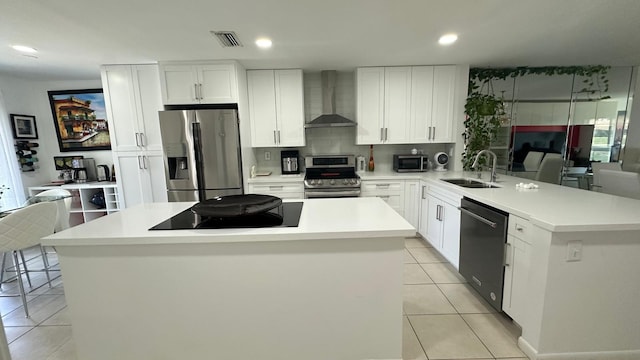 kitchen featuring a center island, white cabinets, sink, wall chimney exhaust hood, and appliances with stainless steel finishes