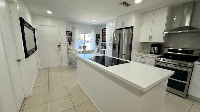 kitchen featuring white cabinetry, a center island, wall chimney exhaust hood, stainless steel appliances, and light tile patterned floors