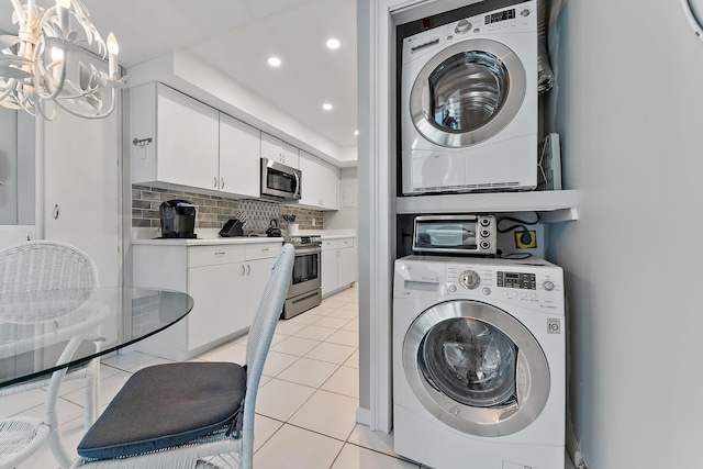 laundry area with stacked washer / dryer and light tile patterned floors