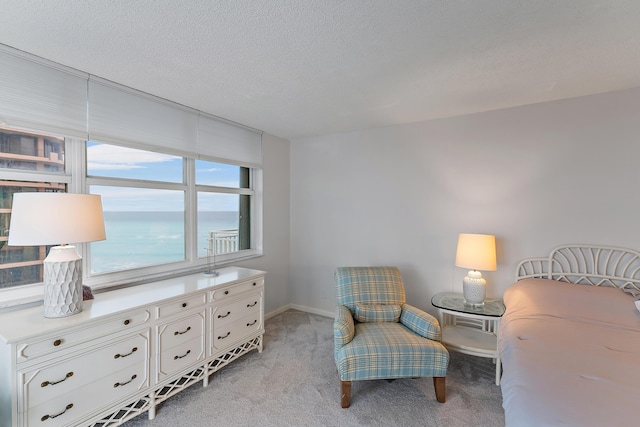 bedroom featuring a textured ceiling, light carpet, and a water view