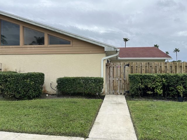 view of property exterior featuring fence, a yard, and stucco siding