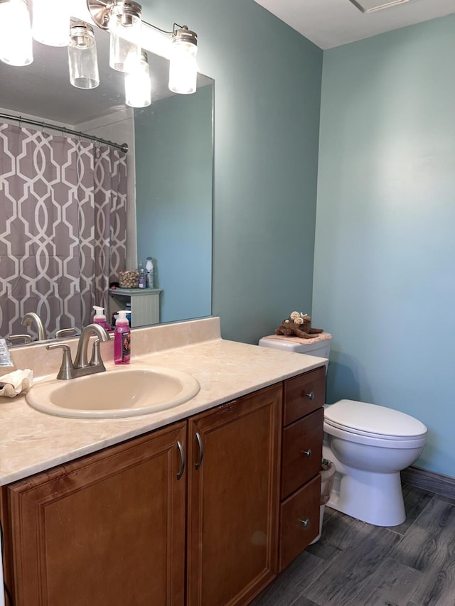 bathroom with toilet, a shower with curtain, vanity, and wood finished floors