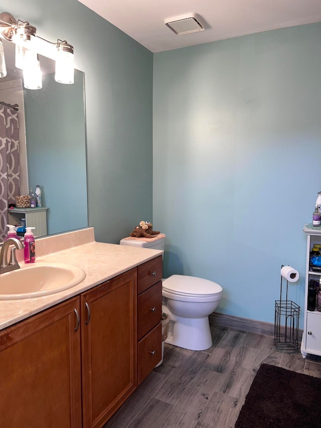 bathroom with vanity, toilet, and hardwood / wood-style flooring