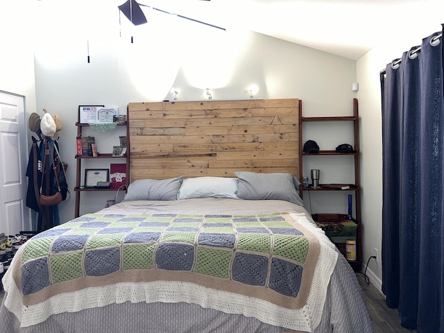 bedroom with vaulted ceiling, wood finished floors, and baseboards