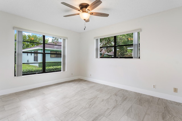 unfurnished room with ceiling fan and a textured ceiling