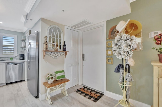 entryway featuring ornamental molding and light hardwood / wood-style flooring