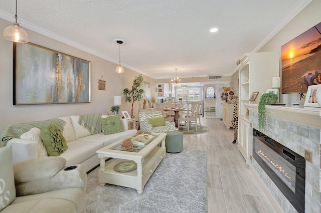 living room with crown molding, a fireplace, a textured ceiling, and a notable chandelier