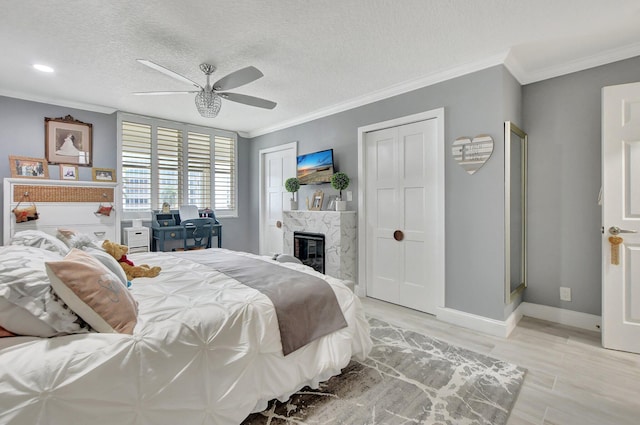 bedroom featuring ceiling fan, a high end fireplace, a textured ceiling, and ornamental molding