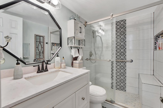 bathroom featuring vanity, toilet, and a shower with door