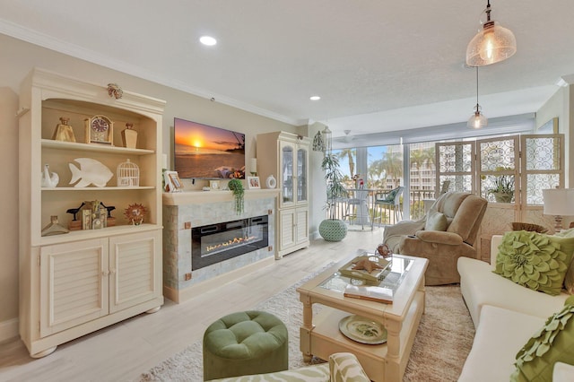 living room featuring built in features, light wood-type flooring, ornamental molding, and a tiled fireplace