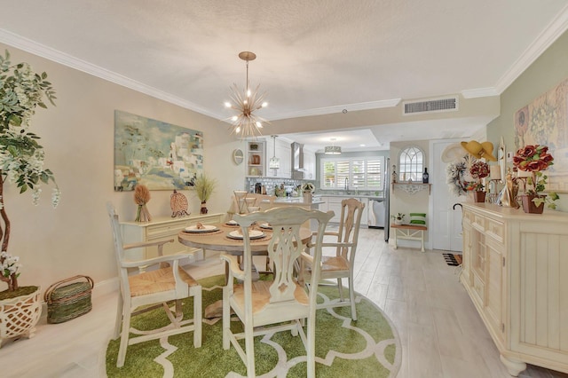 dining area with light hardwood / wood-style flooring, ornamental molding, sink, and an inviting chandelier