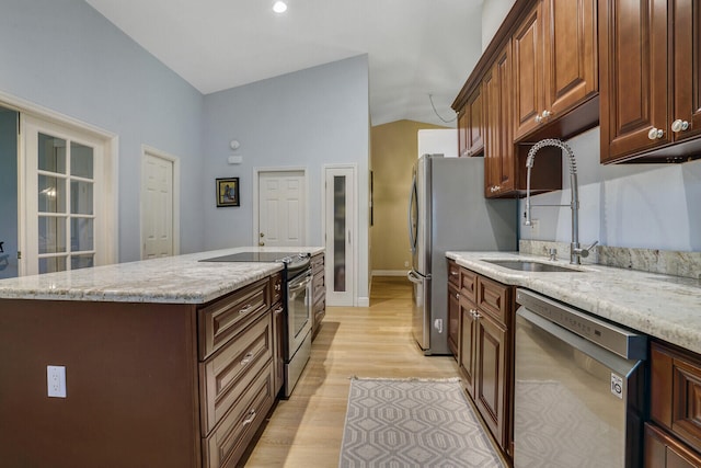 kitchen with sink, light wood-type flooring, a kitchen island, stainless steel appliances, and vaulted ceiling