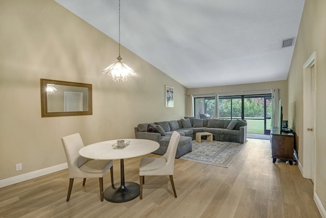 dining room with a chandelier, light hardwood / wood-style flooring, and high vaulted ceiling