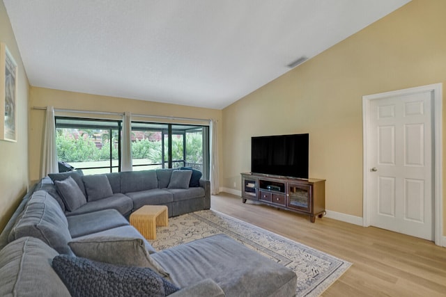 living room with high vaulted ceiling and light hardwood / wood-style flooring