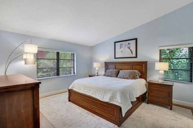 bedroom featuring light hardwood / wood-style flooring, a textured ceiling, and vaulted ceiling