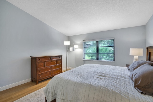 bedroom with a textured ceiling and light wood-type flooring