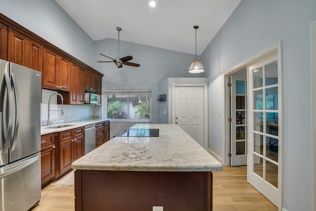 kitchen with appliances with stainless steel finishes, a center island, sink, light hardwood / wood-style floors, and decorative light fixtures