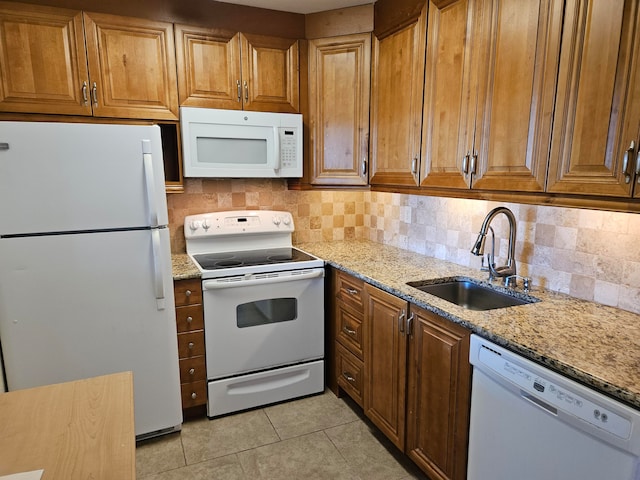 kitchen featuring light stone countertops, sink, backsplash, white appliances, and light tile patterned floors