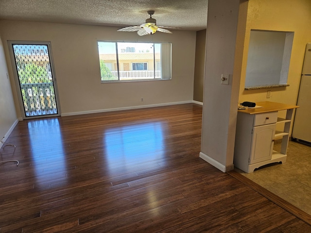 empty room featuring a textured ceiling, ceiling fan, and dark wood-type flooring