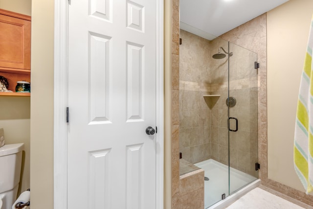 bathroom with a shower with shower door and toilet