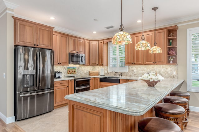 kitchen featuring pendant lighting, appliances with stainless steel finishes, a kitchen bar, and a healthy amount of sunlight