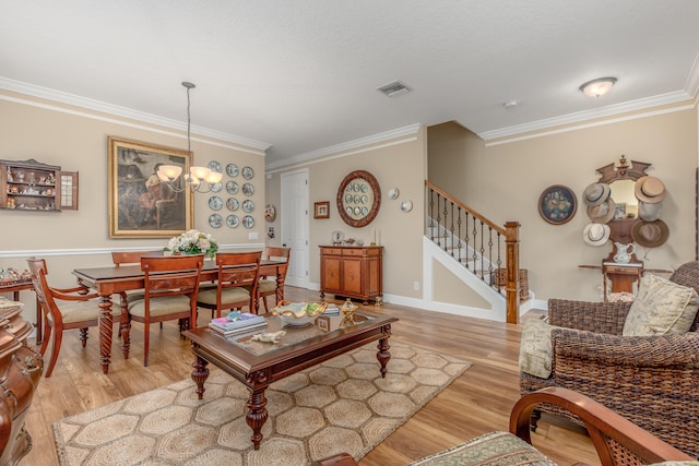 living room featuring ornamental molding, a chandelier, and light hardwood / wood-style floors