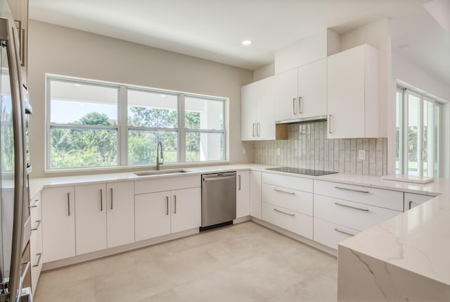 kitchen featuring light stone countertops, stainless steel appliances, plenty of natural light, and white cabinetry