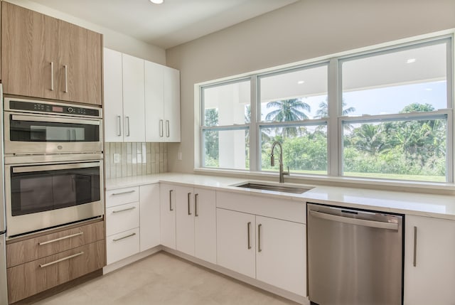 kitchen featuring white cabinets, appliances with stainless steel finishes, sink, and decorative backsplash