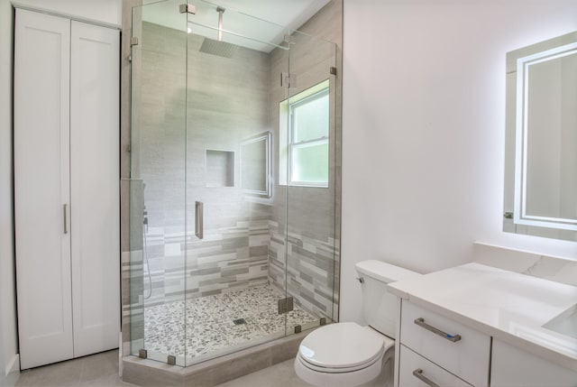 bathroom with tile patterned floors, vanity, walk in shower, and toilet