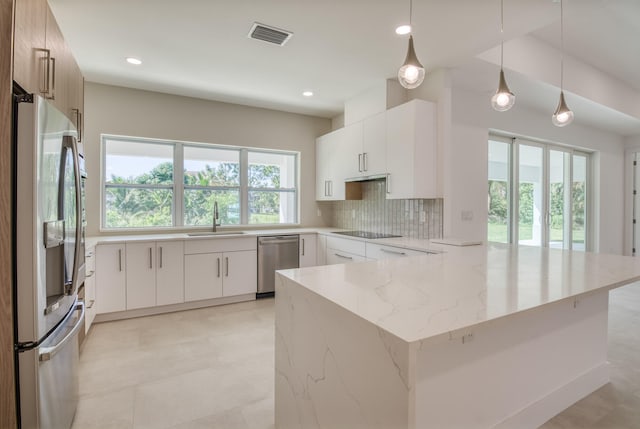 kitchen with decorative light fixtures, sink, decorative backsplash, white cabinets, and appliances with stainless steel finishes